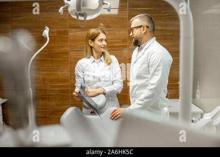 Zwei ältere Zahnärzte in Uniform sprechen im zahnmedizinischen Büro während einer medizinischen Beratung Stockfoto