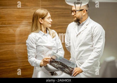 Zwei ältere Zahnärzte in Uniform sprechen im zahnmedizinischen Büro während einer medizinischen Beratung Stockfoto