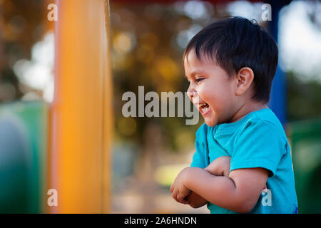 Junge vor Lachen, laut und seine Arme Holding gemeinsam beim Spielen in einem Jungle Gym. Stockfoto