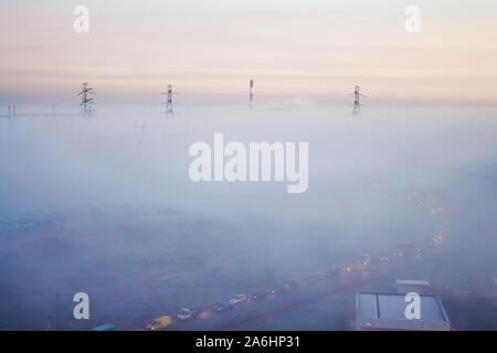 Morgennebel deckt die Fabrik und electrotowers. Ungewöhnliche Landschaft. Autos im Nebel Stockfoto