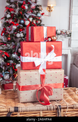 Boxen gebunden mit Bändern auf einer vor dem Hintergrund einer Weihnachtsbaum in roten Farben. Symbol für Glückwünsche und Geschenke für das Neue Jahr und Stockfoto