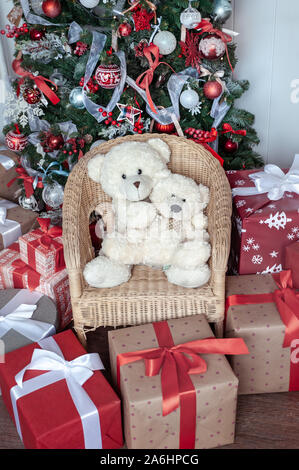Boxen gebunden mit Bändern unter einem Weihnachtsbaum in roten Farben. Symbol für Glückwünsche und Geschenke für das Neue Jahr und Weihnachten. Stockfoto