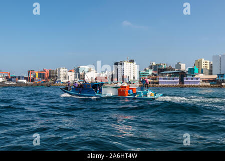 Male, Malediven - November 18, 2017: Transport Boot segeln im Meer auf dem Hintergrund der Insel der Männlichen. Waterfront Stadtbild der männlichen Stadt als se Stockfoto