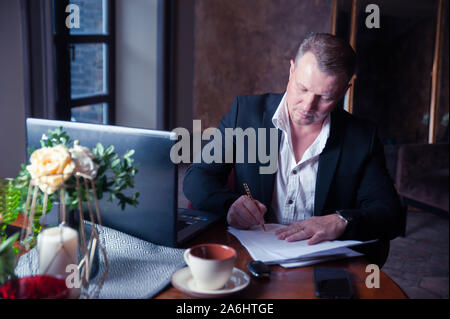 Elegante weiße Mann zeichen Papiere in Luxury Apartments Stockfoto