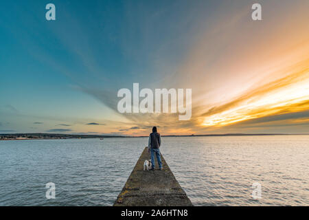 Mann stand auf Pier/Mole mit Blick auf das Meer bei Sonnenaufgang Stockfoto