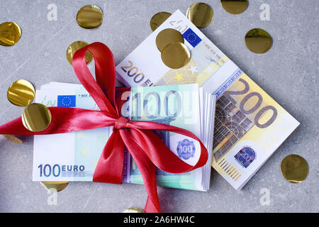 Euro-banknoten auf einem Stapel mit redgift Bug. Geschenk, Prämie oder Belohnung Konzept. Selektiver Fokus Stockfoto