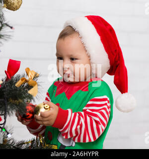 Tricky baby elf Spielen mit Dekorationen auf Weihnachtsbaum Stockfoto