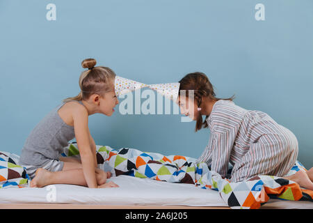 Junge und Mädchen butting Heads, spielen im Schlafzimmer mit Partei kegel Hüte Stockfoto