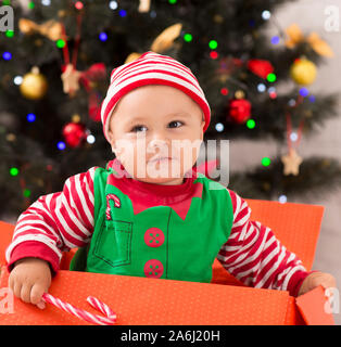 Neugierig Baby elf Sitzen in großen Geschenkbox, auf der Suche nach Weihnachtsgeschenken Stockfoto