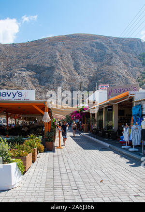 Kamari, Griechenland - 14 Juli 2019: Touristen und Käufer wandern zwischen den Geschäften und Restaurants entlang der Strandpromenade Straße Stockfoto
