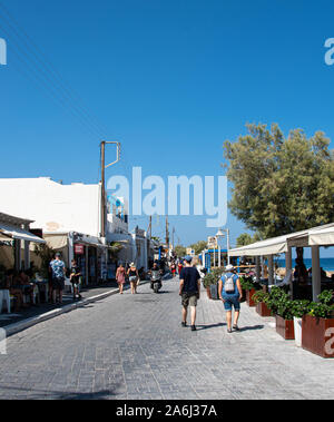 Kamari, Griechenland - 14 Juli 2019: Touristen und Käufer wandern zwischen den Geschäften und Restaurants entlang der Strandpromenade Straße Stockfoto