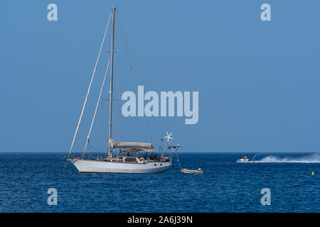 Kamari, Griechenland - 14 Juli 2019: jetski Geschwindigkeiten hinter einem Verankerten Yachtcharter in der Ägäis aus Perissa Strand Stockfoto