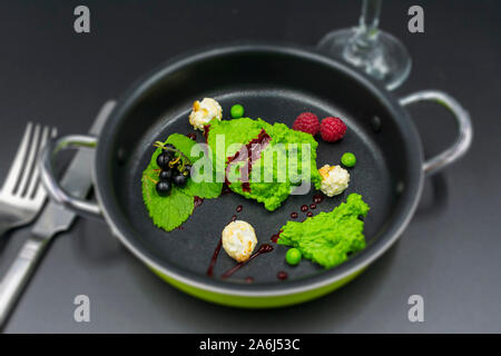 Pea Sorbet mit Minze, Beeren und Popcorn mit unscharfem Hintergrund. Stockfoto