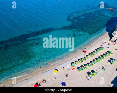 Luftaufnahme von einem Strand mit Sonnenschirmen und Badegäste. Vorgebirge des Heiligtums Santa Maria dell'Isola, Tropea, Kalabrien, Italien. Stockfoto