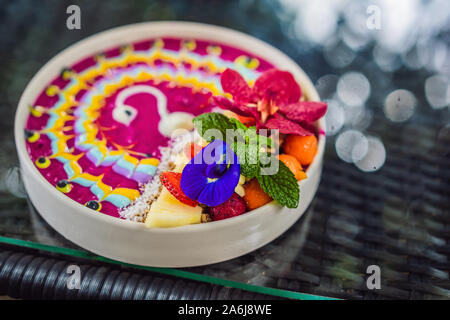 Gesunde tropisches Frühstück, smoothie Schüssel mit tropischen Früchten, dekoriert mit einem Muster von bunten Joghurt mit Gelbwurz und Spirulina. Es ist auch Stockfoto