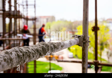 Gerüst ist gegen Gebäude platziert. Chef ist, beaufsichtigt von der Plattform über Baustelle. Stockfoto