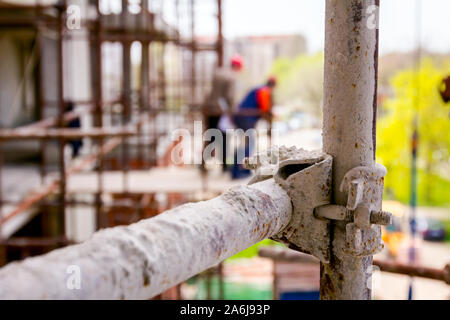 Gerüst ist gegen Gebäude platziert. Chef ist, beaufsichtigt von der Plattform über Baustelle. Stockfoto