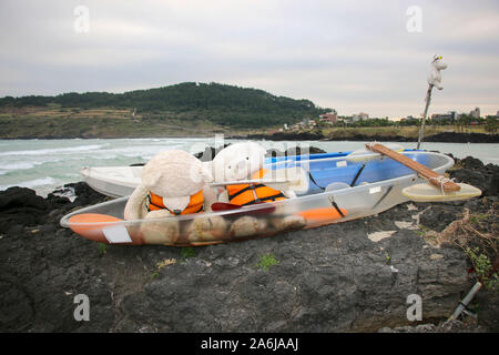 Zwei Teddybären in Schwimmwesten in einem Boot auf einem der Strände auf der Insel Jeju, Südkorea Stockfoto