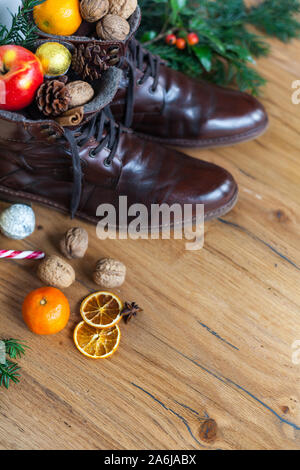 Verständnislos Stiefel mit Süßigkeiten, Nüsse und Äpfel nikolaus Geschenk zu Santa, Holzboden gereinigt Stockfoto