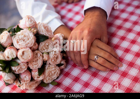 Braut und Bräutigam in der Nähe der Hände mit Ringen und Hochzeit Blumen. Konzept der Hochzeit, Ehe und Familie. Stockfoto