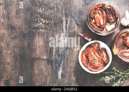 Sonnengetrocknete Tomaten mit Olivenöl in einem Glas auf Holz- Hintergrund. Stockfoto