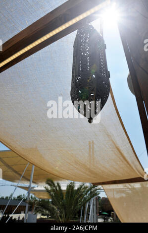 Eine typische arabische Lampe hängt. Sonnensegel für den Hintergrund. Sonnigen Tag. Stockfoto