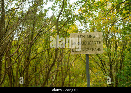Eine Warnung zeigt die Gefahr, die in einem Naturschutzgebiet mit dem Impressum - Achtung Lebensgefahr Abbruchkante (Achtung Gefahr der Abriss bekannte Gefahr o Stockfoto