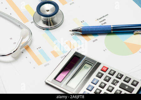 Stethescope, Stift und Taschenrechner mit finanziellen Diagramme und Berichte medizinische Konzept zu veranschaulichen. Stockfoto