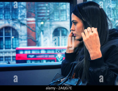 Junge Frau mit ihrem Mobiltelefon auf einem Bus Stockfoto