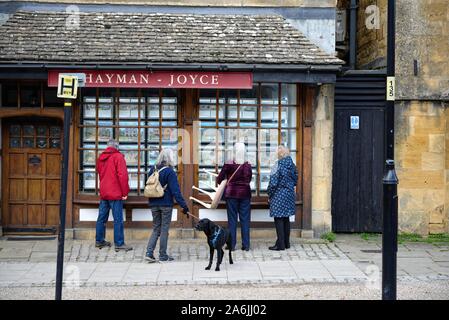 Drei Frauen und ein Mann an der Eigenschaft in einem Immobilienmakler Fenster auf der High Street Broadway Worcestershire England UK angezeigt, Stockfoto