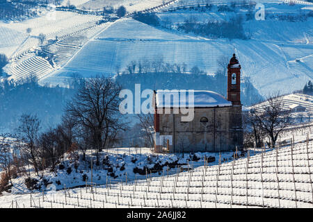 Kleine Pfarrkirche zwischen Weinbergen auf verschneiten Hügel in Piemont, Norditalien. Stockfoto