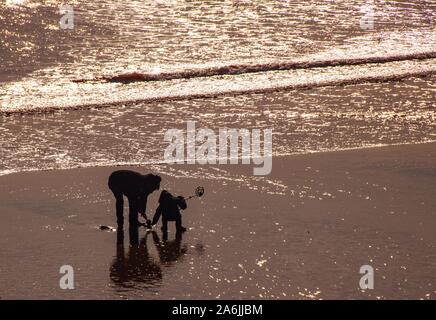 Sidmouth, Großbritannien. 27 Okt, 2019. Eine Familie versuchen Sie ihr Glück mit einem Metalldetektor am Strand von Sidmouth an einem sonnigen, aber kalten Tag an der Küste von Devon. Credit: Foto Central/Alamy leben Nachrichten Stockfoto