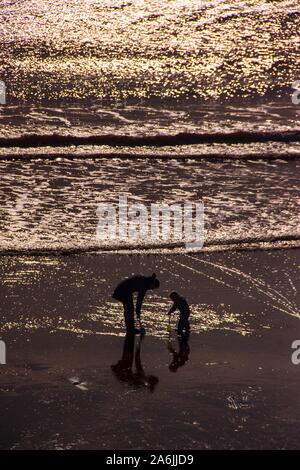 Sidmouth, Großbritannien. 27 Okt, 2019. Eine Familie und genießen Sie die Sonne am Strand trotz eines kühlen Brise in Sidmouth. Credit: Foto Central/Alamy leben Nachrichten Stockfoto