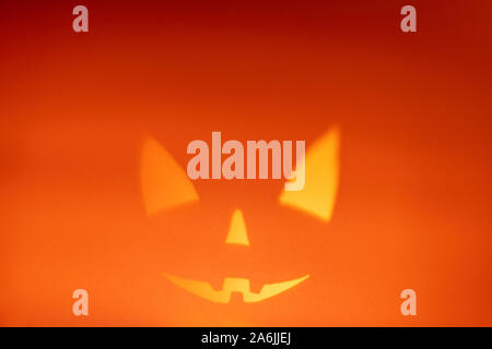 Schatten von Halloween scary pumpkin Gesicht auf dunklen orange Papier Hintergrund. Schatten aus dem Feuer. Halloween Horror Hintergrund. Kopieren Sie Platz. Stockfoto