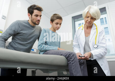 Senior Therapeuten untersuchen Junge mit Reflexhammer Stockfoto