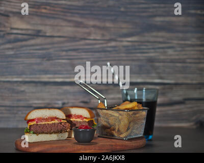 Vegan auf Basis pflanzlicher Burger in der Hälfte mit Pommes auf Holz Tablett serviert. Stockfoto