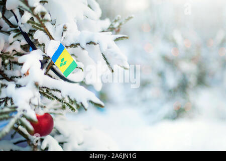 Weihnachten Saint Vincent und die Grenadinen. Xmas Tree mit Schnee, Dekorationen und eine Flagge bedeckt. Verschneite Wald Hintergrund im Winter. Gruß an Weihnachten Stockfoto