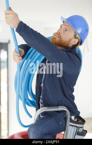 Elektriker ist zur Festsetzung einer elektrischen Wellrohr Stockfoto