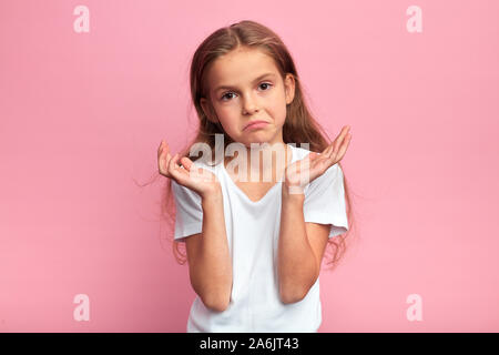 Deprimiert verwirrte arme Mädchen zuckte mit den Schultern, schreiende Kind die Arme heben. ungläubigkeit Konzept. Gesichtsausdruck, Reaktion, isolierte Rosa backgr Stockfoto