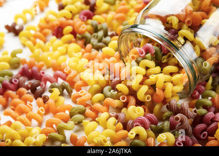 Italienisch bunte Nudeln auf den Tisch aus dem Glas verstreut. Platz für Text Stockfoto