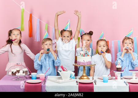 Kleines Mädchen im weißen T-Shirt und ihre Gäste auf einer Party freuen. close up Foto. Isolierte rosa Hintergrund, Studio shot Stockfoto