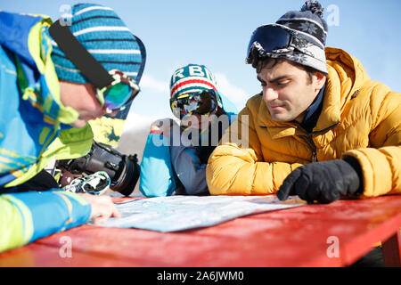 Zwei bemannt und Frau snowboarder Erkundung Karte im Winter Resort am Nachmittag Stockfoto