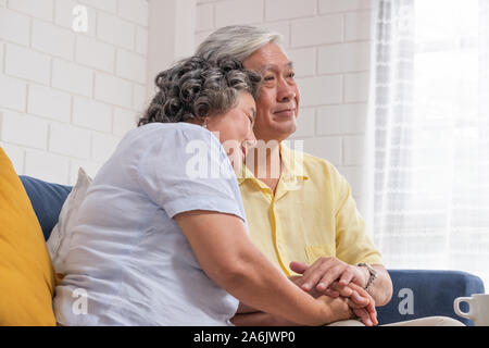 Close up Asiatische senior Paar zusammen, indem sie einander die Hand auf einem Sofa im Wohnzimmer zu Hause ermutigend. glücklichen Ruhestand Lifestyle. Altern zu Hause Stockfoto