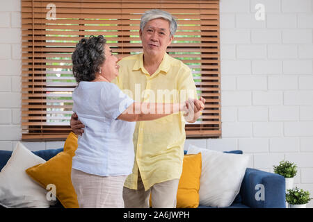 Asiatischer seniors Paar genießen Tanzen im Wohnzimmer zu Hause. Altern zu Hause Konzept Stockfoto