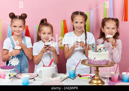 Gerne kleine Kinder kleine Kuchen essen. Isolierte rosa Hintergrund, Studio erschossen. glückliche Kindheit, bis schließen Foto Stockfoto