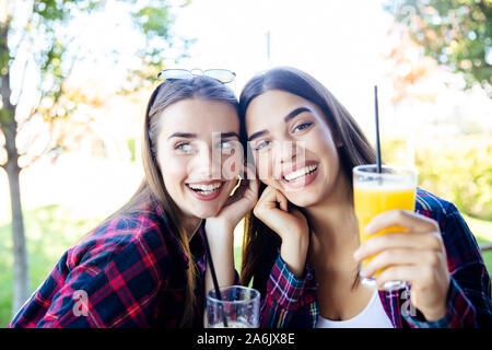 Zwei junge Frauen trinken Saft und Limonade in den Park an einem sonnigen Tag Stockfoto