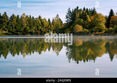 See Bibi (Bibisee) in Bayern im Herbst mit Reflexionen von bunten t und ein blauer Himmel aboverees auf der Wasseroberfläche Stockfoto