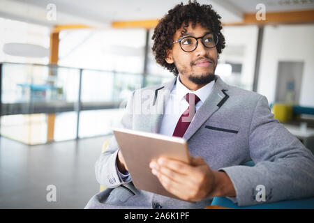 Lächelnd Portrait von schwarzer Geschäftsmann mit Touchscreen tablet device im Büro Stockfoto