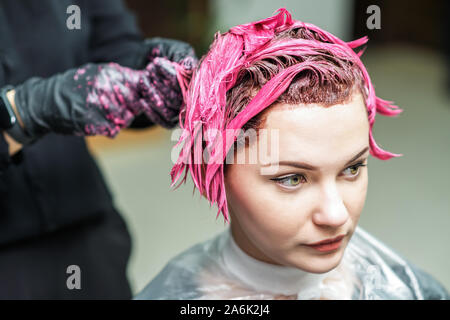 Friseur Hände sind die rosa Farbe der Haare. Haare färben in einem Schönheitssalon. Schönheit und Personen Konzept. Stockfoto