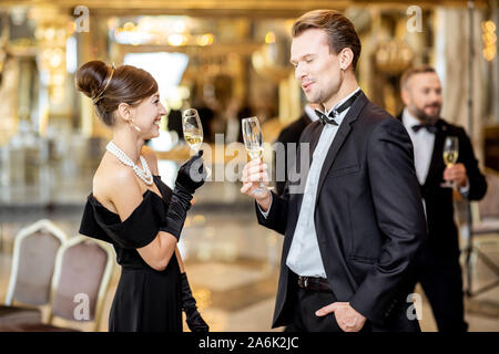 Gut gekleidete Paar in retro styles Spaß, trinken Wein im luxuriösen Restaurant Halle während der großartigen Feier des neuen Jahres Urlaub Stockfoto